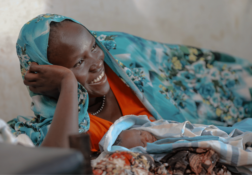 A new mother smiles with relief and joy — a reflection of the quality care and compassion midwife Gizachew brings to every delivery.